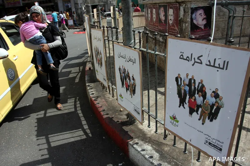 A Palestinian woman walks past an electoral campaign displaying portraits of candidates running for municipal elections on October 6, 2012 in the West Bank city of Ramallah. Campaigning has started in the West Bank for t...