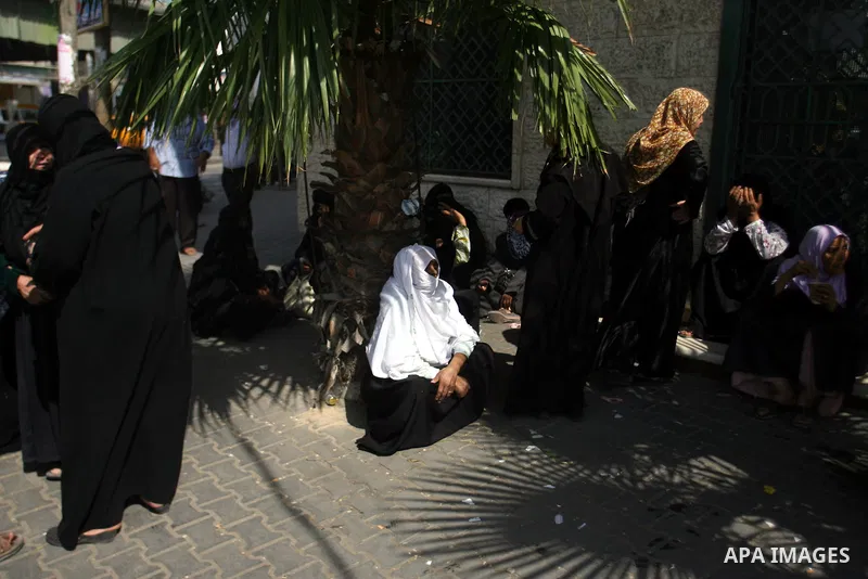 Palestinians wait in front of a center for Social Affairs to receive the financial aid during the program of the Ministry of Social Affairs to help the people with special needs, in Rafah in southern Gaza strip, Oct. 07,...