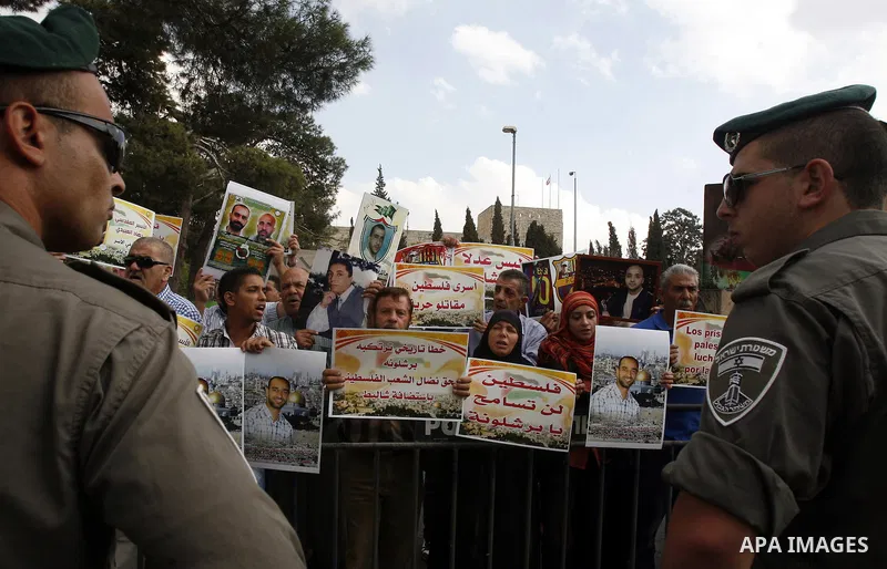 Families of Palestinian prisoners in Israeli jails hold their portraits and placards, bearing a portrait of Israeli soldier Gilad Shalit on the emblem of Spanish FC Barcelona football club, during a demonstration outside...