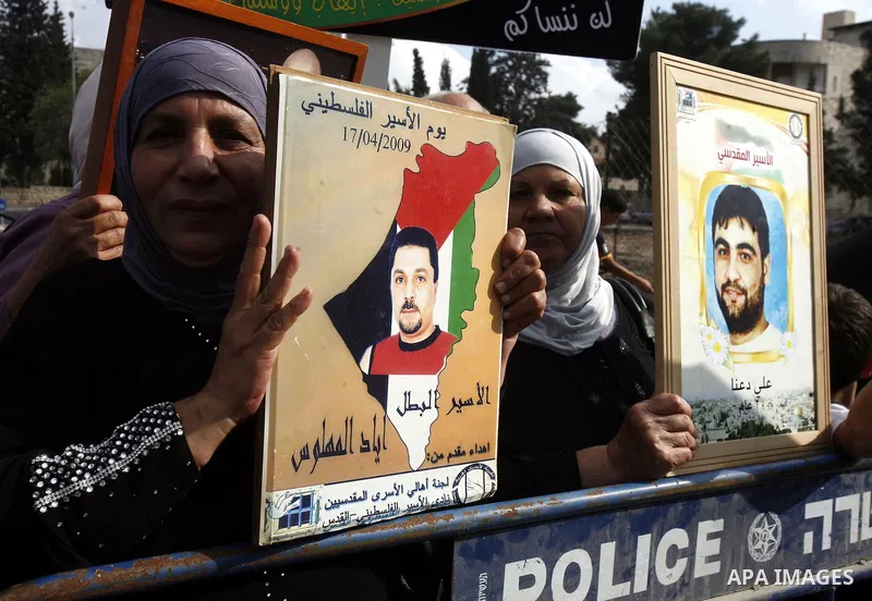 Families of Palestinian prisoners in Israeli jails hold their portraits and placards, bearing a portrait of Israeli soldier Gilad Shalit on the emblem of Spanish FC Barcelona football club, during a demonstration outside...