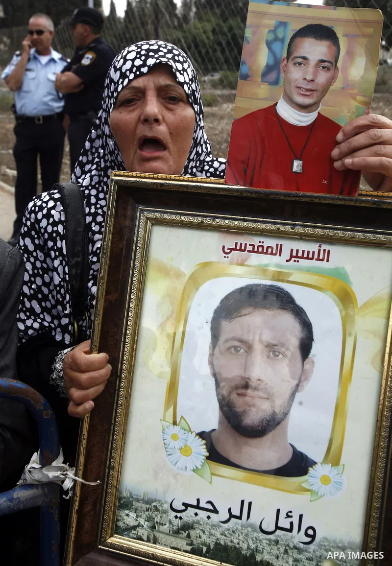 Families of Palestinian prisoners in Israeli jails hold their portraits and placards, bearing a portrait of Israeli soldier Gilad Shalit on the emblem of Spanish FC Barcelona football club, during a demonstration outside...
