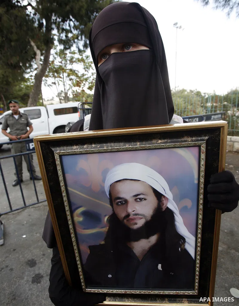 Families of Palestinian prisoners in Israeli jails hold their portraits and placards, bearing a portrait of Israeli soldier Gilad Shalit on the emblem of Spanish FC Barcelona football club, during a demonstration outside...