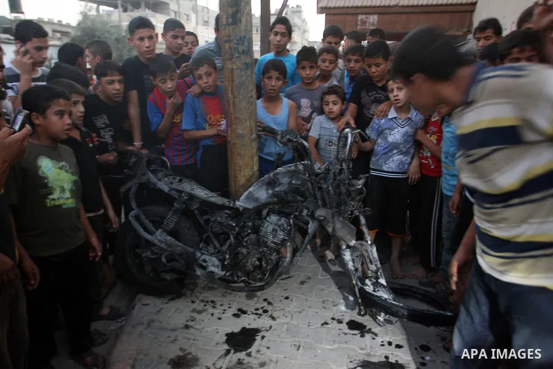 Palestinians gather around a destroyed motorcycle following an Israeli air strike in Rafah camp in the southern Gaza Strip October 7, 2012. A missile fired by an Israeli aircraft hit and wounded two Palestinian militants...