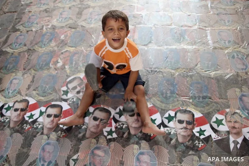 A Syrian boy hits on pictures of Syrian President Bashar Al-Assad by his slipper in the city of Aleppo on September 08 2012. Photo by Ahmed Deeb