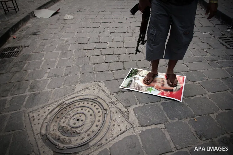 A Syrian rebel fighter stands on a picture of Syrian President Bashar al-Assad, in the Old Town of Aleppo, September 11, 2012 during clashes with Syrian government forces to retake control of the large Hanano army base i...