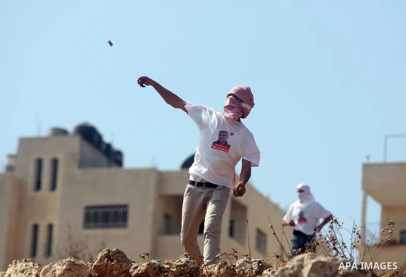 A Palestinian protester hurls stones towards the Israeli soldiers during clashes outside Israel's Ofer military prison, near the West Bank city of Ramallah on October 10, 2012, following a demonstration to demand the rel...
