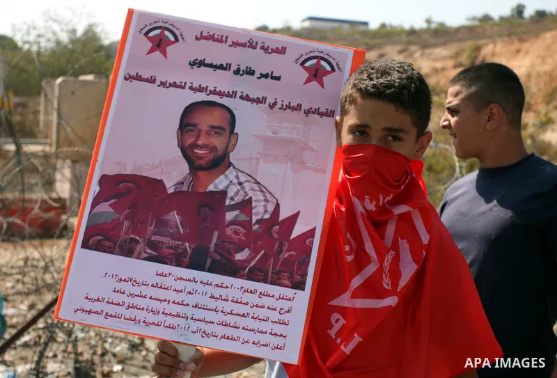 A Palestinian protester holds a portrait of prisoners in Israeli jails during a demonstration to call for their realease, outside Israel's Ofer military prison, near the West Bank village of Betunia west of Ramallah, on...