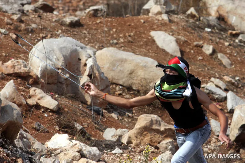 A Palestinian protester hurls stones towards the Israeli soldiers during clashes outside Israel's Ofer military prison, near the West Bank city of Ramallah on October 10, 2012, following a demonstration to demand the rel...
