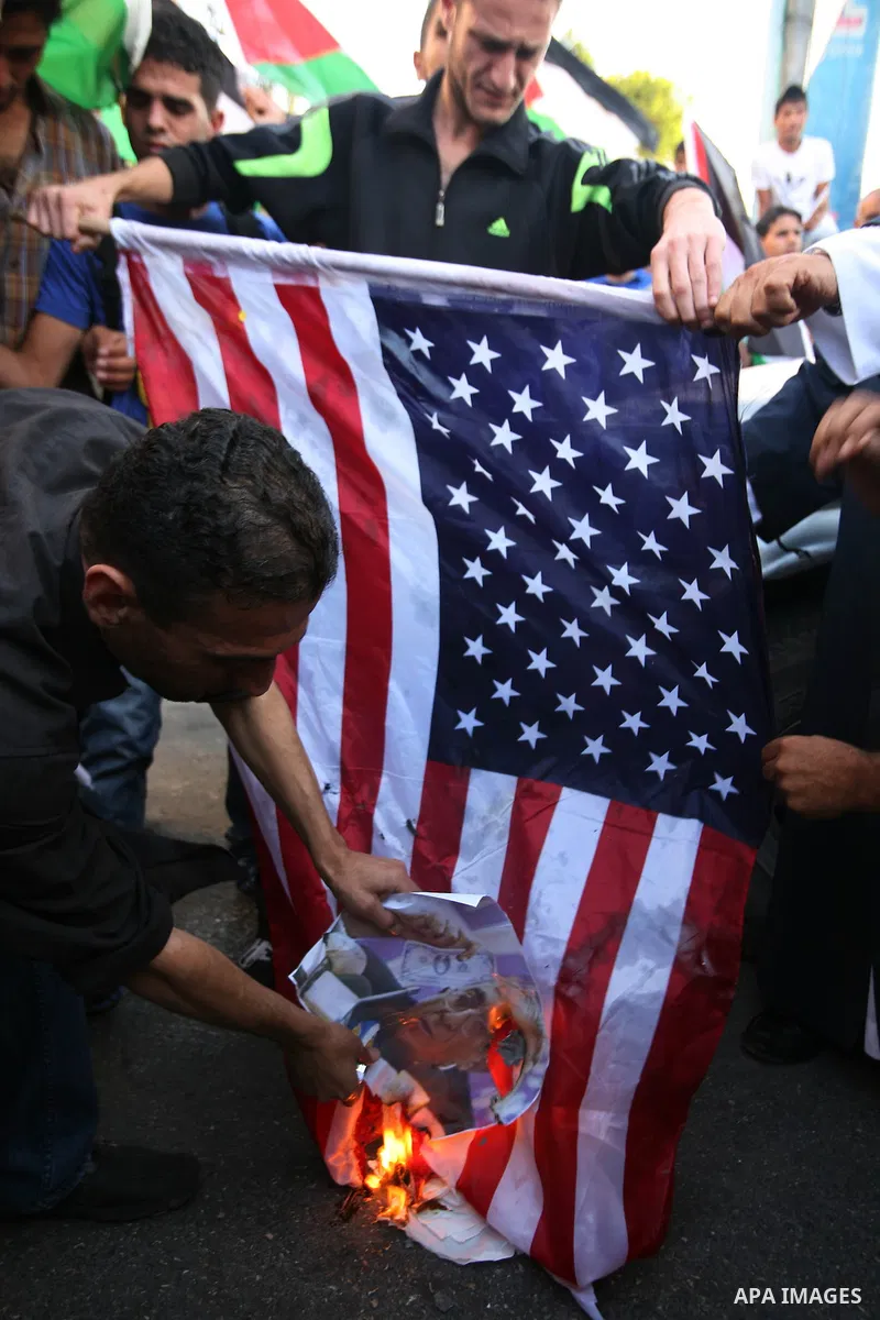 Palestinian protesters burn the US flag and pictures of Palestinian Prime Minister during a demonstration against the financial politics of Prime Minister Salam Fayyad and the high cost of living, in the West Bank city o...