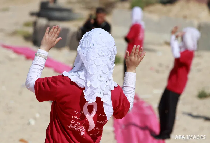 Palestinian youths stand on a beach in Gaza City near a pink ribbon as part of the Breast Cancer Awareness campaign on October 10, 2012. Photo by Majdi Fathi