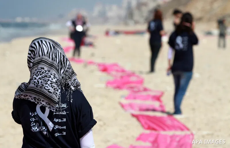 Palestinian youths stand on a beach in Gaza City near a pink ribbon as part of the Breast Cancer Awareness campaign on October 10, 2012. Photo by Majdi Fathi