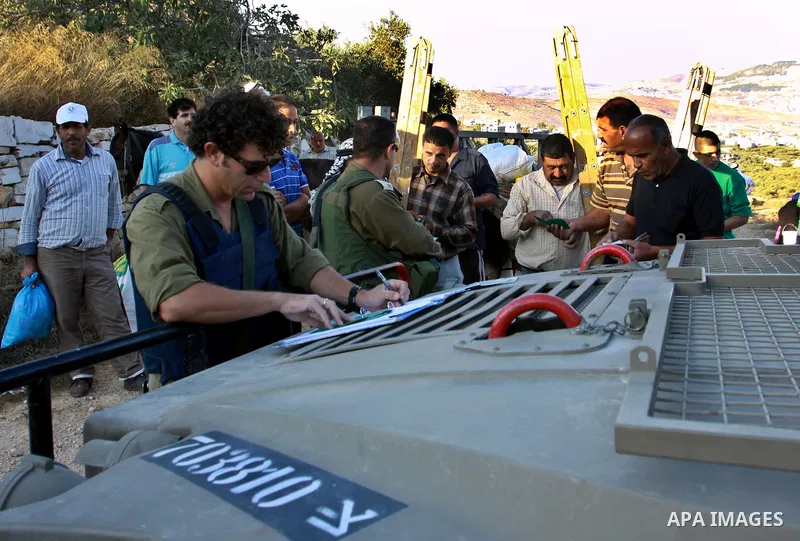 Israeli soldiers check Palestinians Identities as they make their way to harvest olive trees on the outskirts of the West Bank village of Salem, near the Jewish settlement of Elone Moreh, east of Nablus October 11, 2012....