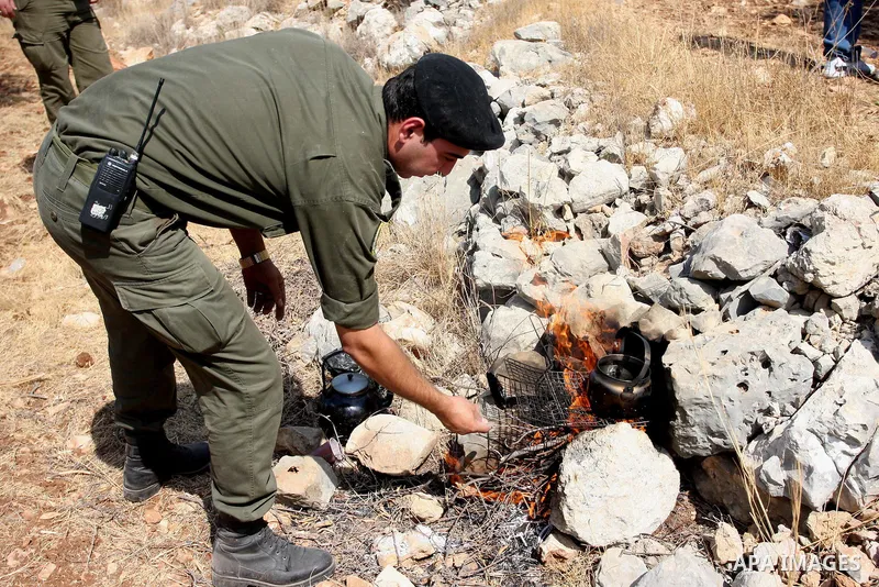 A members of the Palestinian security forces makes a pitcher of tea as others help farmers collect harvest their olives, in the West bank village of Kafr Nimih, near Ramallah, 11 October 2012. Palestinian national forces...
