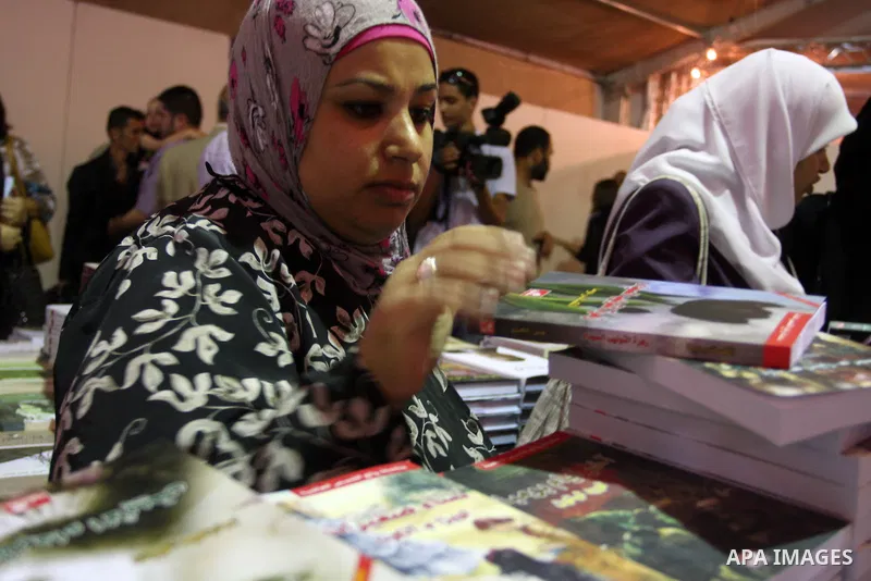 Palestinian visitors read books at a booth during the launch of the Palestine Book Fair Exhibition, in the West Bank city of Ramallah , Oct. 11, 2012. The Palestine 8th Book Fair has participated with more than 200 publi...