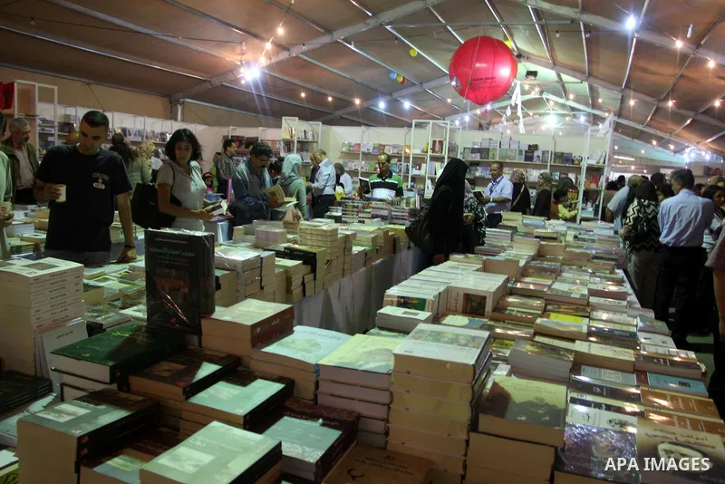 Palestinian visitors read books at a booth during the launch of the Palestine Book Fair Exhibition, in the West Bank city of Ramallah , Oct. 11, 2012. The Palestine 8th Book Fair has participated with more than 200 publi...