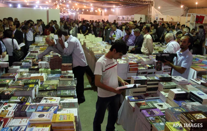 Palestinian visitors read books at a booth during the launch of the Palestine Book Fair Exhibition, in the West Bank city of Ramallah , Oct. 11, 2012. The Palestine 8th Book Fair has participated with more than 200 publi...