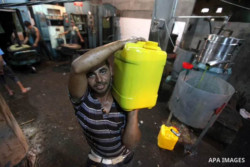 A Palestinian worker carry an olive oil can after it was extracted from an olive press in Gaza City on Oct. 12, 2012. Agriculture is a major sector of the Palestinian economy, employing a large part Palestinians. Photo b...