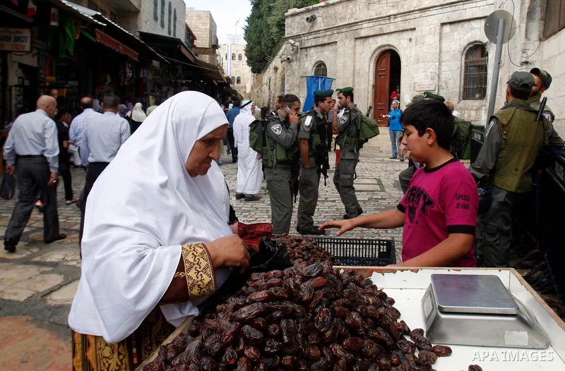 A Palestinian woman shops at the market in the al-Aqsa mosque compound, Islam's third holiest site, as Israeli police officers stand guard after the Friday prayers, in Jerusalem's old city on Oct. 12, 2012. Photo by Mahf...