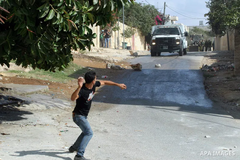 A Palestinian protester throws stones towards Israeli soldiers during a demonstration against the expropriation of Palestinian land by Israel in the village of Kfar Qaddum, near the occupied West Bank city of Nablus, on...