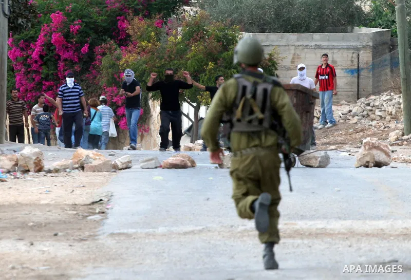 An Israeli soldier run after palestinian protesters during clashes in the weekly protest against the Jewish settlement of Qadomem, near Nablus, West Bank, 12 October 2012. Israeli troops arrested three protesters during...