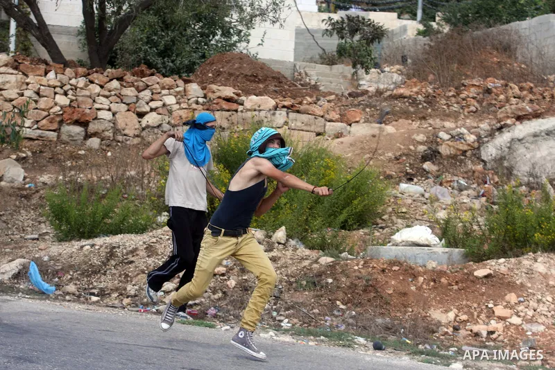 Palestinian protesters throw stones at Israeli soldiers during clashes after a weekly protest against the expansion of the nearby Jewish settlement of Halamish, in the West Bank village of Nabi Saleh, near Ramallah, Frid...