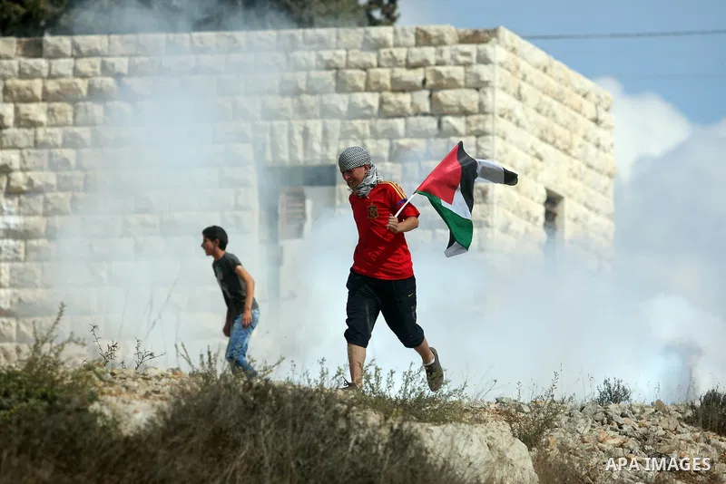 Palestinian protesters run from tear gas fired by Israeli soldiers during clashes after a weekly protest against the expansion of the nearby Jewish settlement of Halamish, in the West Bank village of Nabi Saleh, near Ram...