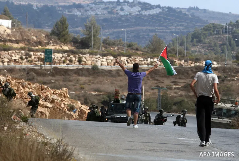 Palestinian protesters hold national flag during a weekly protest against the expansion of the nearby Jewish settlement of Halamish, in the West Bank village of Nabi Saleh, near Ramallah, Friday, Oct 12, 2012. Photo by I...