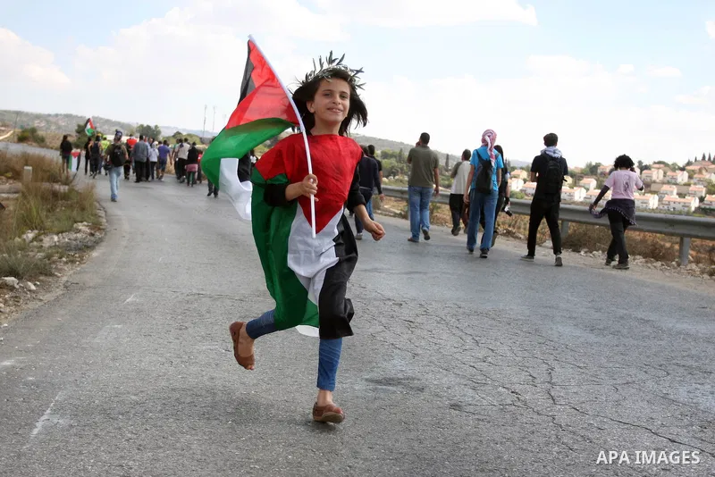 A Palestinian girl wears national flag during a weekly protest against the expansion of the nearby Jewish settlement of Halamish, in the West Bank village of Nabi Saleh, near Ramallah, Friday, Oct 12, 2012 . Photo by Iss...