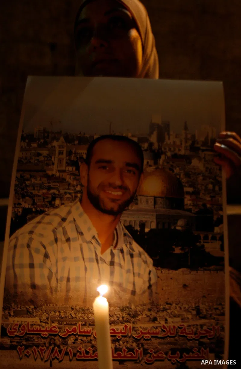 A Palestinian woman holds picture of prisoners and candles during a protest calling for the release of Palestinian prisoners from Israeli jails and in support of inmates on hunger strike, outside Damascus Gate in Jerusal...