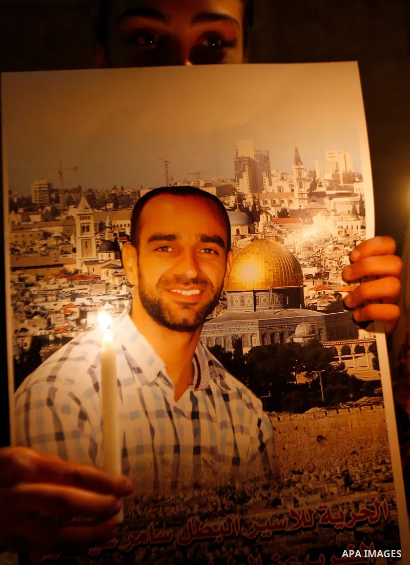 A Palestinian man holds picture of prisoners and candles during a protest calling for the release of Palestinian prisoners from Israeli jails and in support of inmates on hunger strike, outside Damascus Gate in Jerusalem...
