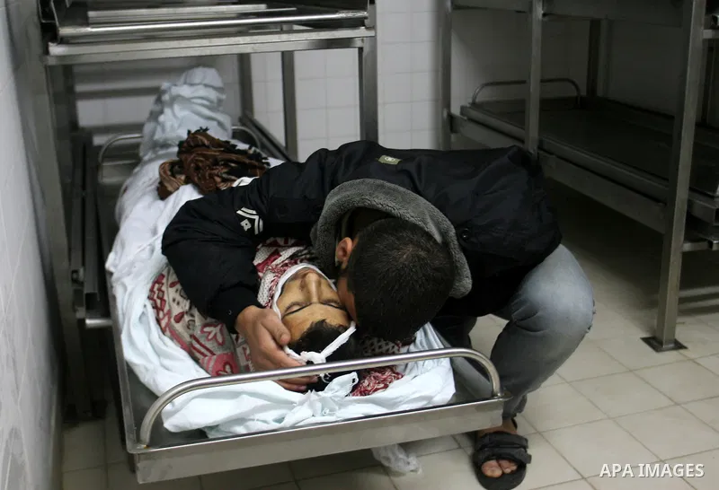 A Palestinian looks at the body of Yasser Al Attal in hospital morgue following an Israeli airstrike in area "Al fokhari" in east of Khan Younis in the southern Gaza Strip, on October 14, 2012. An Israeli air strike Satu...
