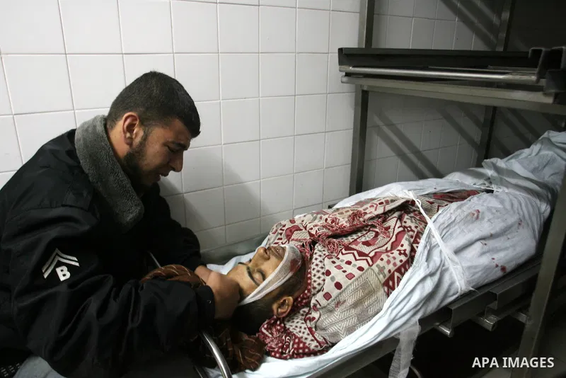 A Palestinian looks at the body of Yasser Al Attal in hospital morgue following an Israeli airstrike in area "Al fokhari" in east of Khan Younis in the southern Gaza Strip, on October 14, 2012. An Israeli air strike Satu...