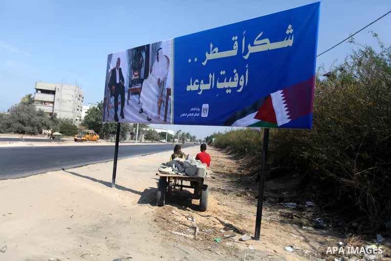 Palestinians ride their cart pass a street placard reads in Arabic "Thank Qatar for fit promise" on October 15, 2012. A Qatari delegation headed by Ambassador Mohammed al-Emadi has arrived in Gaza through the Rafah cross...