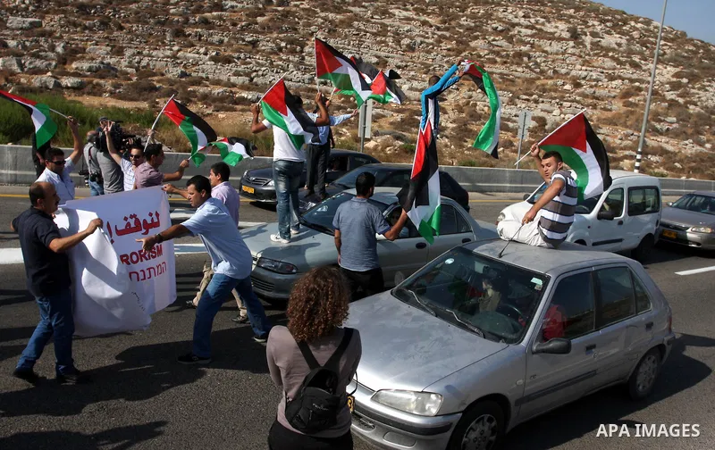 Activists hold Palestinian flags in front of Israeli troops during a protest on highway 443 near the West Bank village of Beit Ur against what they say are attacks by Jewish settlers on Palestinians and their property, O...