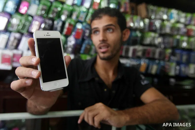 A Palestinian man holds Apple's new iPhone 5 at a mobile phone store in Gaza City on October 16, 2012. Apple's new iPhone 5 is selling well in the Gaza Strip despite inflated prices, reaching the Palestinian enclave via...