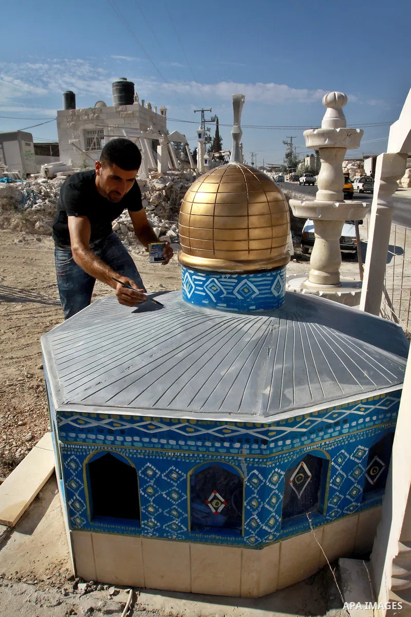 A Palestinian artist colors a model of the Dome of the Rock mosque made by marble stones, in the West Bank city of Nablus on Oct. 17, 2012. Photo by Nedal Eshtayah
