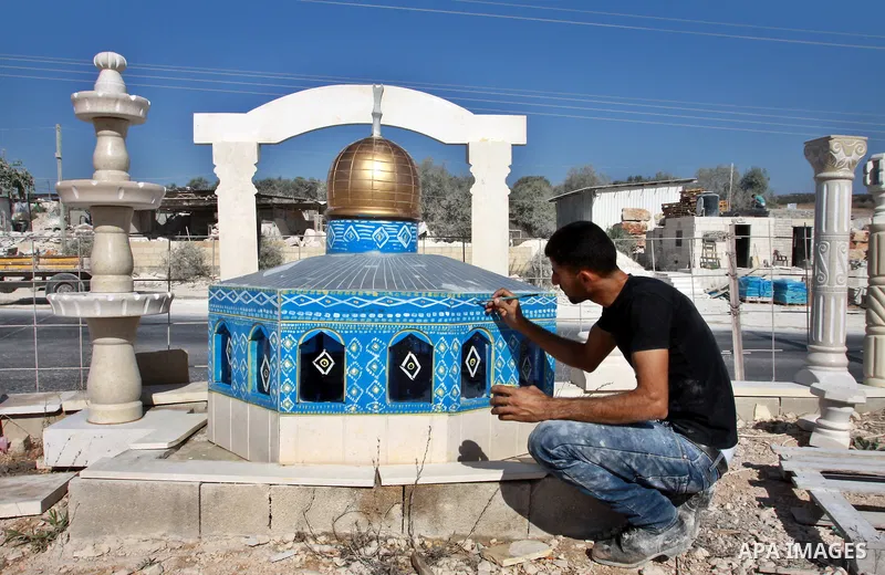 A Palestinian artist colors a model of the Dome of the Rock mosque made by marble stones, in the West Bank city of Nablus on Oct. 17, 2012. Photo by Nedal Eshtayah