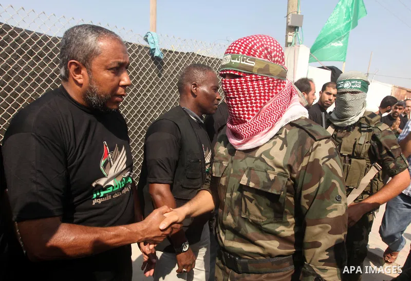 Abu Obaida (C), the spokesman for the Ezzedine Al-Qassam Brigades, the armed wing of Hamas, shakes the hands of the freed Palestinians during a news conference on October 18, 2012 at the Rafah border crossing with Egypt...