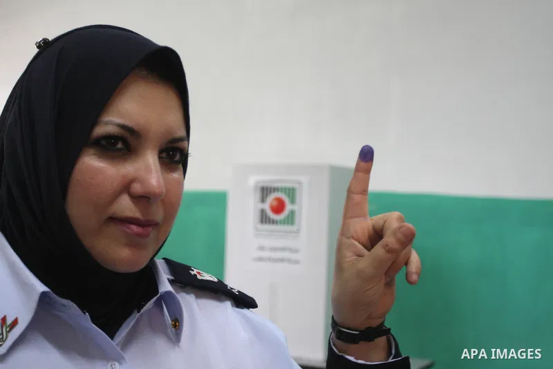 A Palestinian police officer shows her ink-stained finger after casting an early vote during local elections at a polling station in the West Bank town of Ramallah, 18 October 2012. The polling stations will be open from...