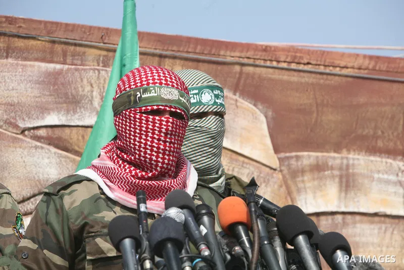 Abu Obaida (L), the spokesman for the Ezzedine Al-Qassam Brigades, the armed wing of Hamas, speaks during a news conference on October 18, 2012 at the Rafah border crossing with Egypt in the southern Gaza Strip to mark t...