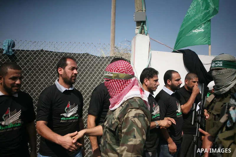 Abu Obaida (C), the spokesman for the Ezzedine Al-Qassam Brigades, the armed wing of Hamas, shakes the hands of the freed Palestinians during a news conference on October 18, 2012 at the Rafah border crossing with Egypt...