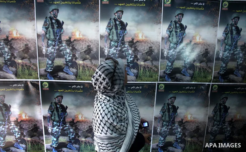 A Palestinian woman walks pass next to portrait during a ceremony to mark the first anniversary of a deal which saw the exchange of 1,027 Palestinian prisoners for captured Israeli soldier Gilad Shalit, in Gaza city on 1...