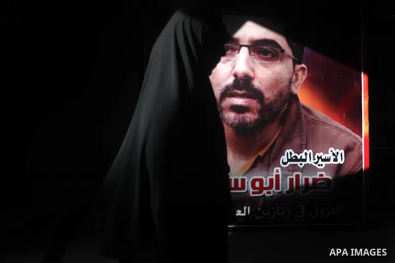 A Palestinian woman walks pass next to a portrait of a Palestinian prisoner during a ceremony to mark the first anniversary of a deal which saw the exchange of 1,027 Palestinian prisoners for captured Israeli soldier Gil...
