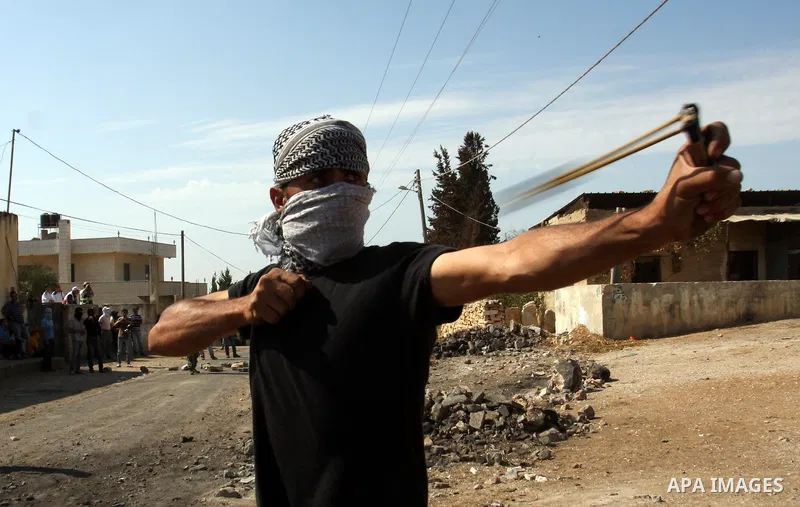 A Palestinian protester hurls stones on towards Israeli soldiers during clashes following a demonstration against the expropriation of Palestinian land by Israel in the village of Kfar Qaddum, near the occupied West Bank...