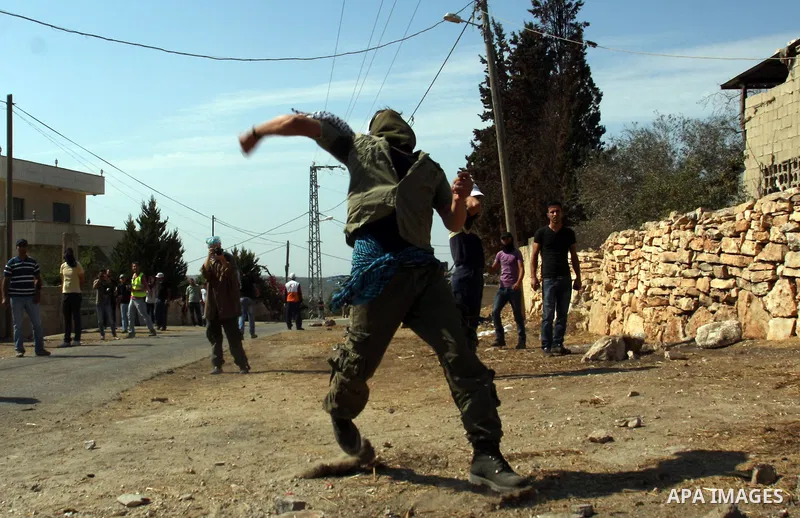 A Palestinian protester throws stones on towards Israeli soldiers during clashes following a demonstration against the expropriation of Palestinian land by Israel in the village of Kfar Qaddum, near the occupied West Ban...