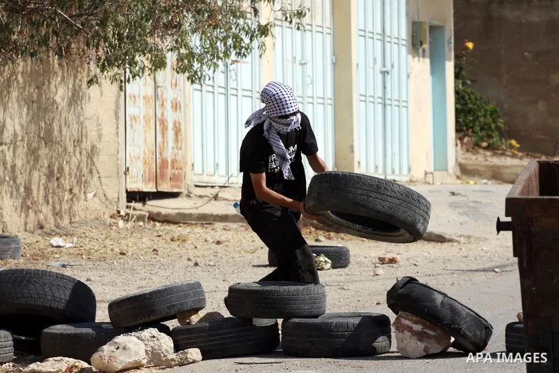 A Palestinian protester carries a tire to burn it during clashes with Israeli soldiers following a demonstration against the expropriation of Palestinian land by Israel in the village of Kfar Qaddum, near the occupied We...