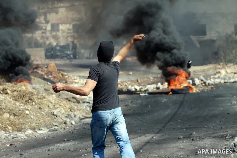A Palestinian protester throws stones on towards Israeli soldiers during clashes following a demonstration against the expropriation of Palestinian land by Israel in the village of Kfar Qaddum, near the occupied West Ban...