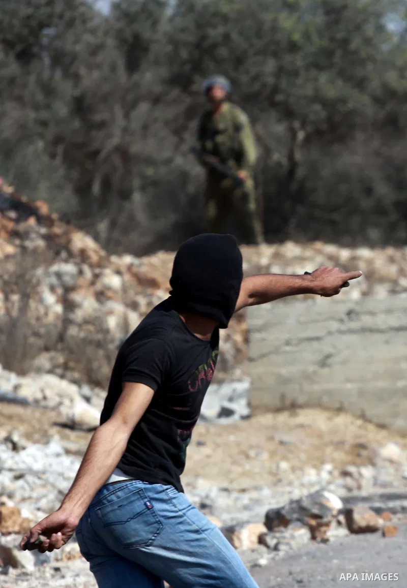 A Palestinian protester throws stones on towards Israeli soldiers during clashes following a demonstration against the expropriation of Palestinian land by Israel in the village of Kfar Qaddum, near the occupied West Ban...