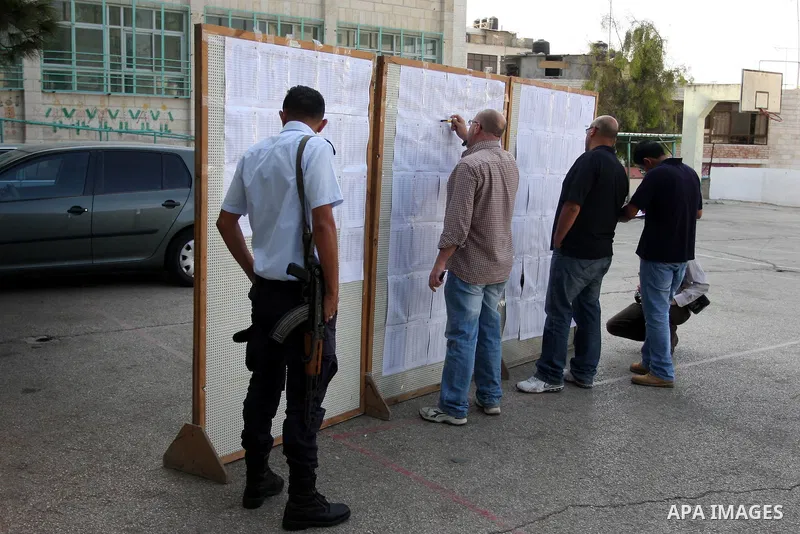 Palestinians look for his name on the registered voters' list outside a polling station in the West Bank city of Ramallah on October 20, 2012. Ballot booths opened across the West Bank as Palestinians began voting in loc...