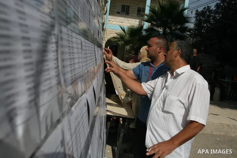 Palestinians look for his name on the registered voters' list outside a polling station in the West Bank city of Ramallah on October 20, 2012. Ballot booths opened across the West Bank as Palestinians began voting in loc...